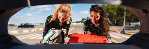 Dwie młode kobiety pakujące bagażnik samochodu podczas podróży – mobilność z SIXT DriveSmart