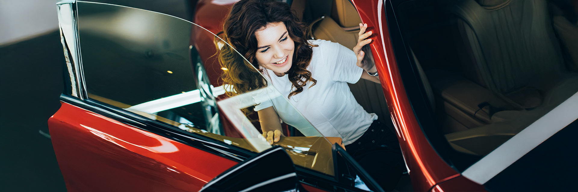 Kobieta wsiadająca do nowoczesnego czerwonego samochodu – wynajem długoterminowy SIXT DriveSmart.