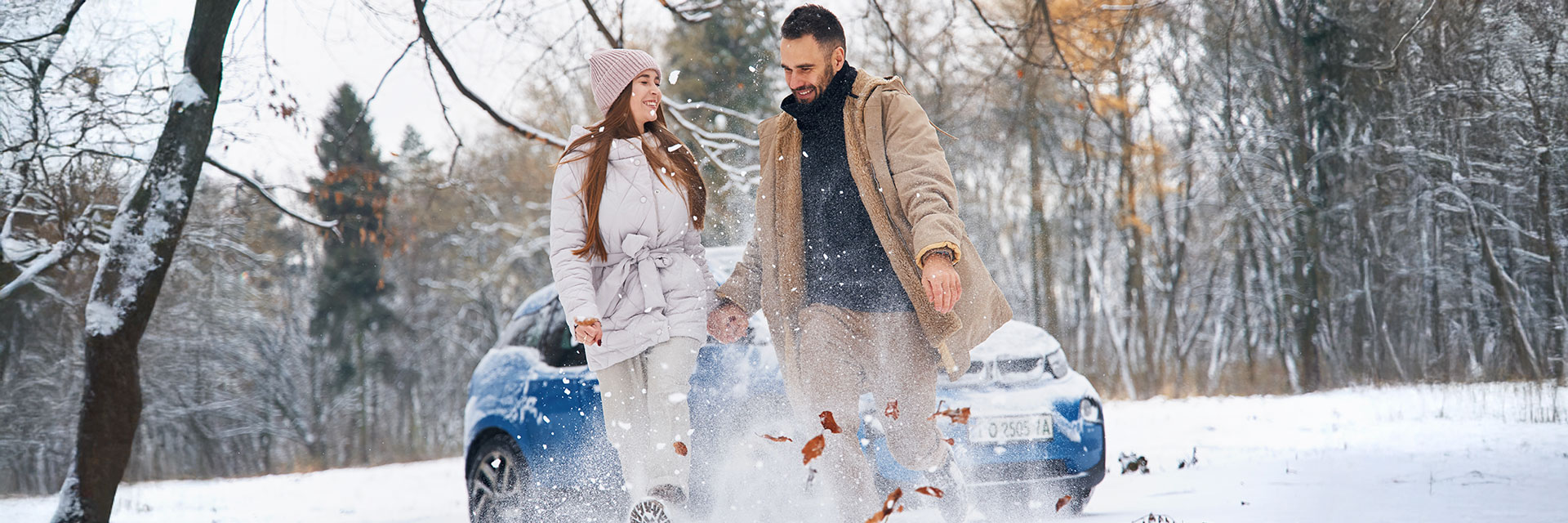 Para spacerująca zimą po zaśnieżonej drodze obok zaparkowanego samochodu z oferty SIXT DriveSmart – komfortowa i bezpieczna podróż w sezonie zimowym.