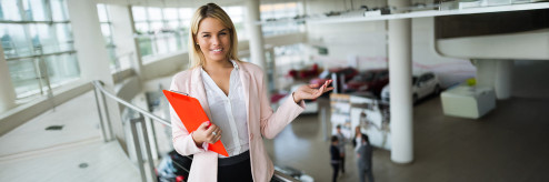 Kobieta w salonie samochodowym prezentująca ofertę nowoczesnej mobilności od SIXT DriveSmart