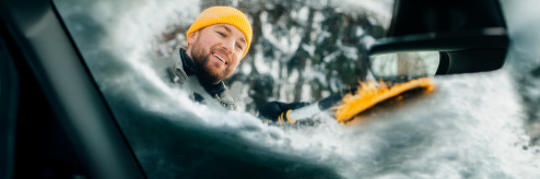 Kierowca odśnieżający samochód zimą – bezpieczna mobilność z SIXT DriveSmart