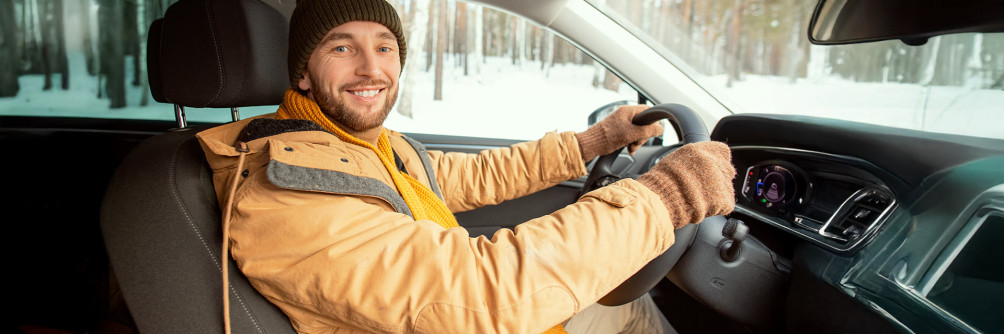 Uśmiechnięty kierowca zimą w nowoczesnym aucie – wynajem długoterminowy SIXT DriveSmart