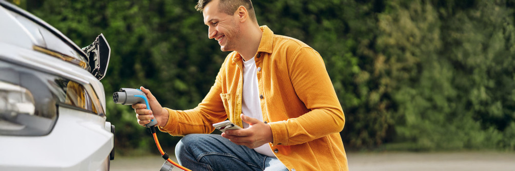 mężczyzna ładuje samochód elektryczny wynajem auta elektrycznego oszczędność paliwa SIXT
