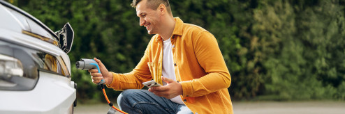 mężczyzna ładuje samochód elektryczny wynajem auta elektrycznego oszczędność paliwa SIXT