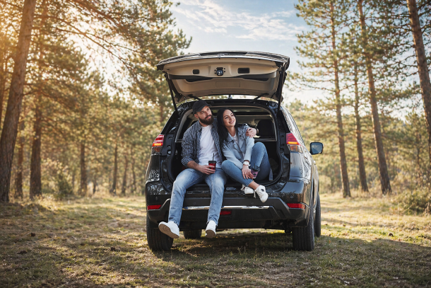 Para siedzi w bagażniku samochodu podczas majówkowego wyjazdu – wynajem auta na majówkę SIXT DriveSmart