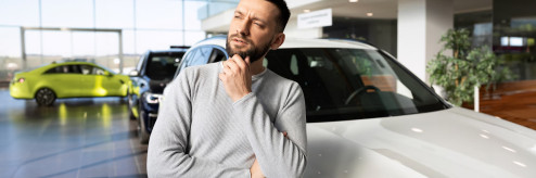 Mężczyzna analizujący wybór samochodu w salonie – zakup czy wynajem długoterminowy SIXT DriveSmart