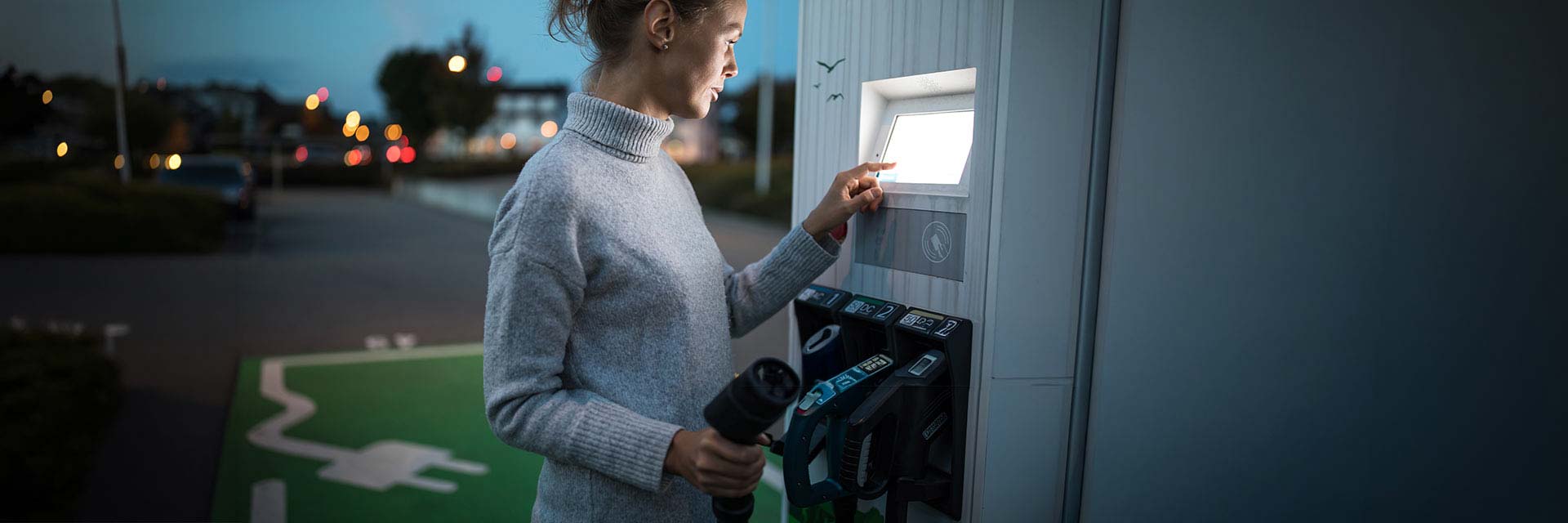Kobieta korzystająca z publicznej stacji ładowania samochodów elektrycznych